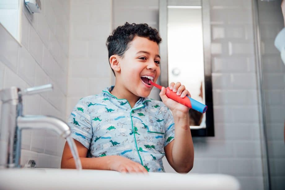 Young child brushing teeth with electric toothbrush