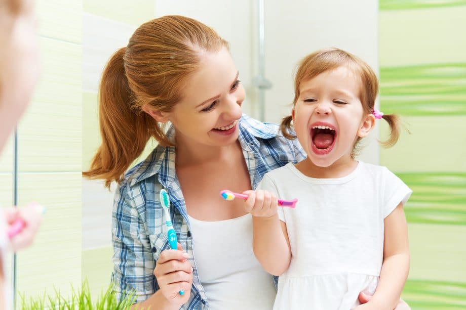 mom and toddler daughter in bathroom brushing teeth