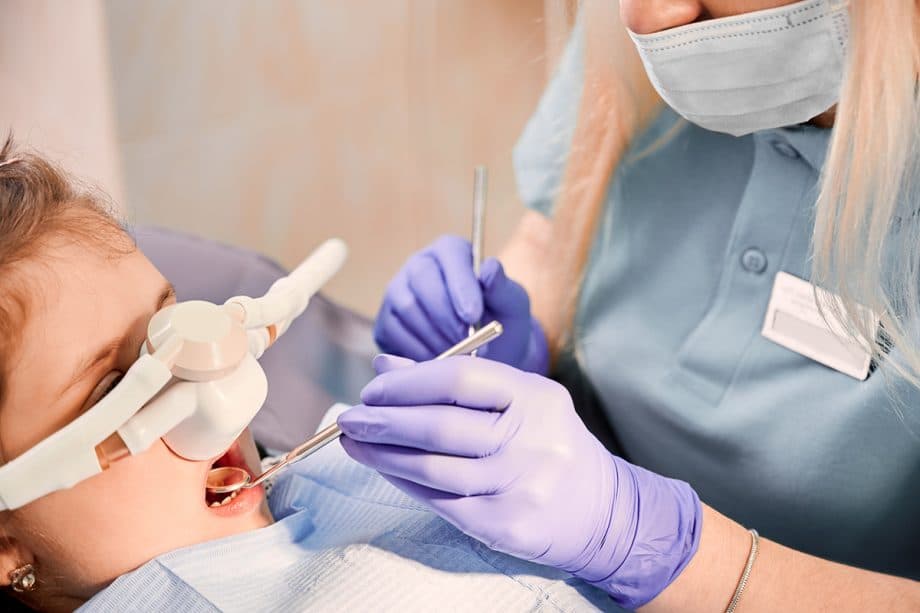 young girl getting sedation while dentist examines her mouth