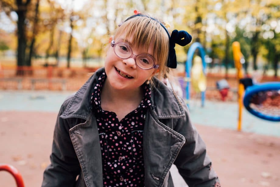 smiling young girl with glasses on playground